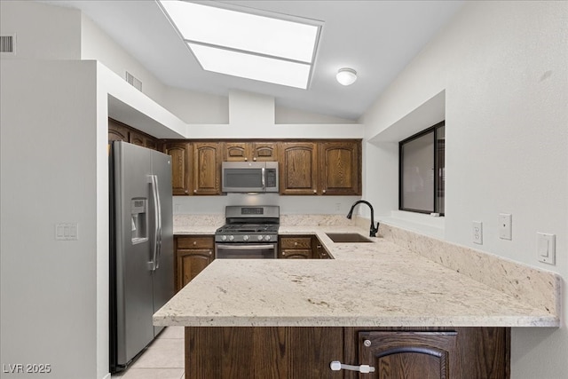 6997 Ray Charles Ln, Las Vegas, NV 89119 - kitchen featuring stainless steel appliances, a sink, lofted ceiling, a peninsula, and light tile patterned flooring