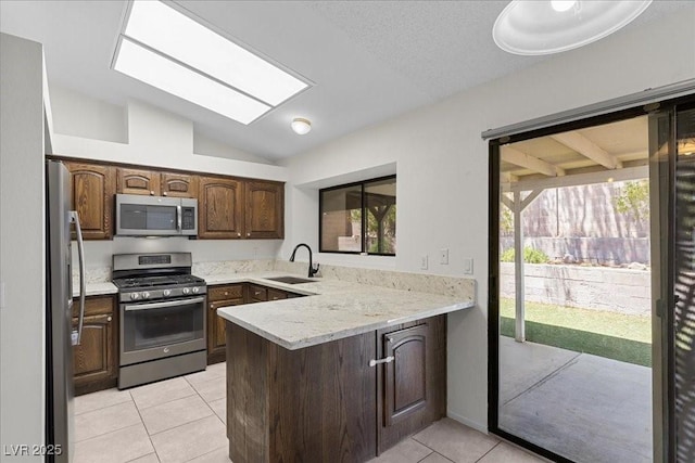 6997 Ray Charles Ln, Las Vegas, NV 89119 - kitchen with appliances with stainless steel finishes, vaulted ceiling, a peninsula, a sink, and light tile patterned flooring