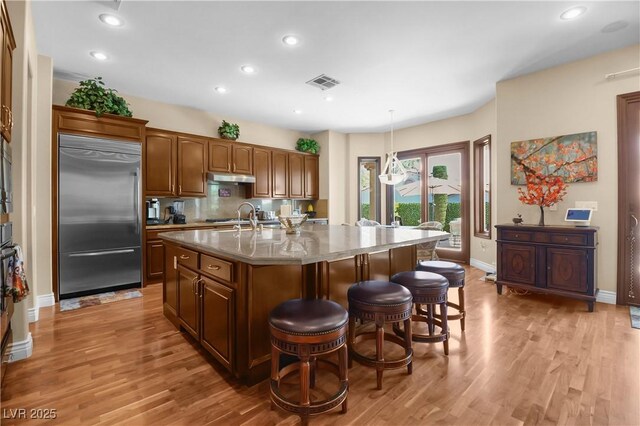 4208 Agosta Luna Pl, Las Vegas, NV 89135 - kitchen featuring built in refrigerator, under cabinet range hood, an island with sink, light wood-type flooring, and recessed lighting