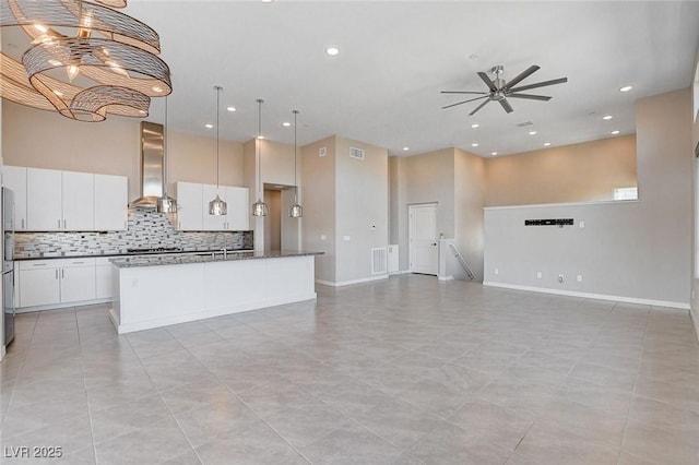 10985 Limeslice Ave Unit 2, Las Vegas, NV 89135 - kitchen with wall chimney range hood, open floor plan, ceiling fan, decorative backsplash, and a center island with sink