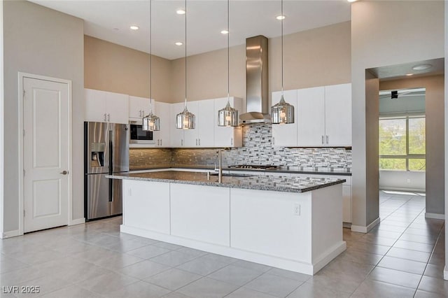 10985 Limeslice Ave Unit 2, Las Vegas, NV 89135 - kitchen featuring appliances with stainless steel finishes, wall chimney exhaust hood, tasteful backsplash, a center island with sink, and a high ceiling