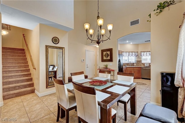 9370 Corkfish St, Las Vegas, NV 89178 - dining area featuring a high ceiling, arched walkways, stairway, a chandelier, and light tile patterned floors