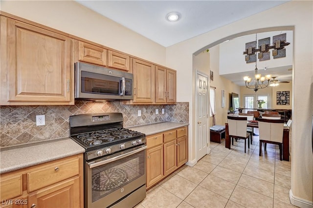 9370 Corkfish St, Las Vegas, NV 89178 - kitchen with stainless steel appliances, a chandelier, arched walkways, light tile patterned floors, and light countertops