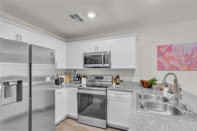 2598 Polar White Ave, North Las Vegas, NV 89086 - kitchen with appliances with stainless steel finishes, a sink, light countertops, white cabinets, and a peninsula