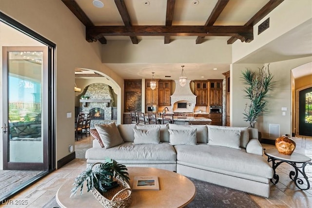 20 Via Paradiso St, Henderson, NV 89011 - living room featuring a lit fireplace, beam ceiling, arched walkways, light stone finish flooring, and recessed lighting