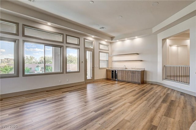 9921 Mirada Dr, Las Vegas, NV 89144 - unfurnished living room with wet bar, light wood-style flooring, recessed lighting, and beverage cooler