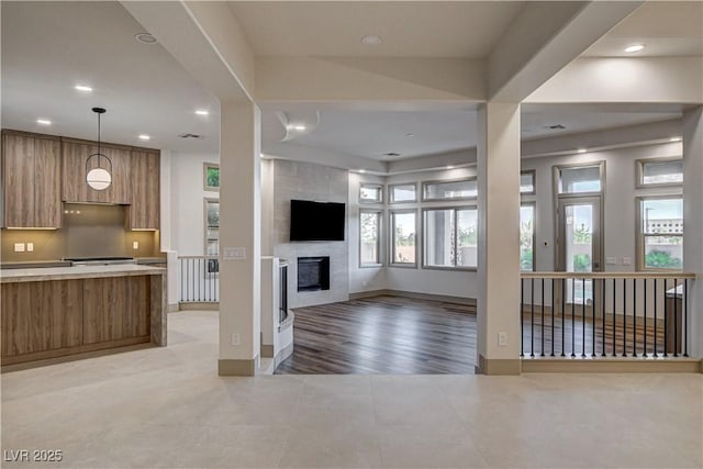 9921 Mirada Dr, Las Vegas, NV 89144 - kitchen with modern cabinets, brown cabinets, light tile patterned floors, a large fireplace, and light countertops