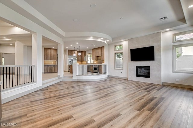 9921 Mirada Dr, Las Vegas, NV 89144 - unfurnished living room with light wood-type flooring, a tiled fireplace, recessed lighting, and baseboards