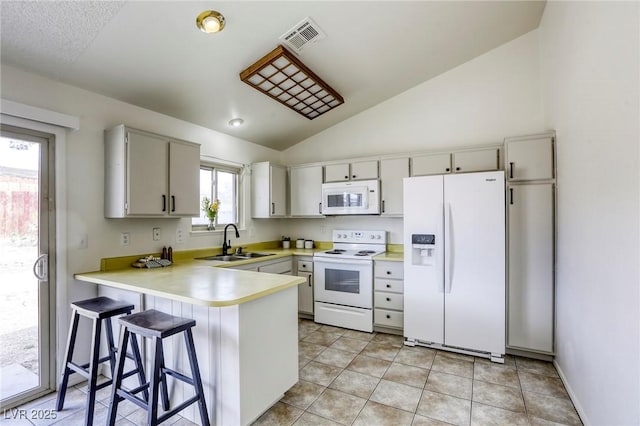 1012 Winwood St, Las Vegas, NV 89108 - kitchen with white appliances, a peninsula, a sink, vaulted ceiling, and light countertops