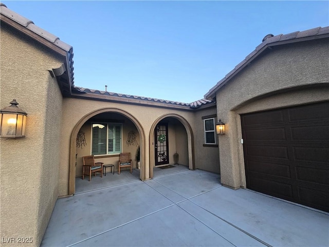 4242 Helena Hideaway Ct, Las Vegas, NV 89129 - property entrance with stucco siding, an attached garage, a tile roof, and covered porch