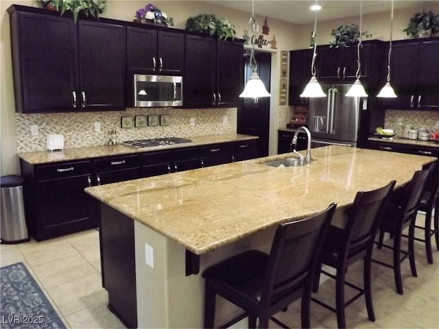 4242 Helena Hideaway Ct, Las Vegas, NV 89129 - kitchen with stainless steel appliances, a sink, light stone counters, tasteful backsplash, and light tile patterned floors