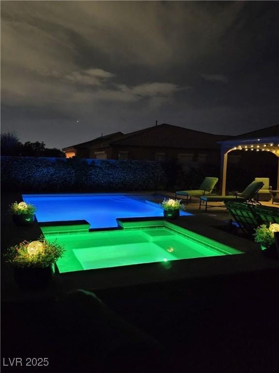 4242 Helena Hideaway Ct, Las Vegas, NV 89129 - pool at night featuring a pool with connected hot tub and a patio area