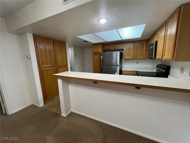8940 Antioch Way, Las Vegas, NV 89117 - kitchen with appliances with stainless steel finishes, dark colored carpet, brown cabinets, a peninsula, and light countertops