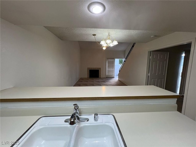 8940 Antioch Way, Las Vegas, NV 89117 - kitchen with a sink, a chandelier, a fireplace, light countertops, and a textured ceiling