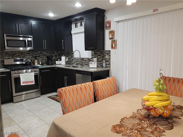 266 Lyra Ln, Las Vegas, NV 89110 - kitchen with stainless steel appliances, dark cabinetry, a sink, and tasteful backsplash