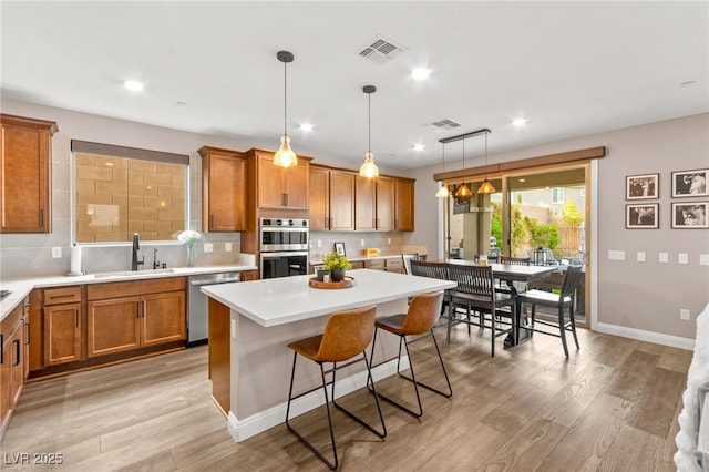 12430 Foxtail Run Ave, Las Vegas, NV 89138 - kitchen featuring stainless steel appliances, a sink, brown cabinets, backsplash, and light countertops