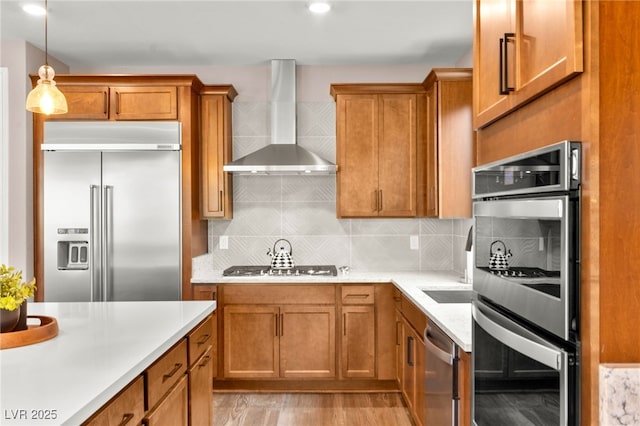 12430 Foxtail Run Ave, Las Vegas, NV 89138 - kitchen featuring stainless steel appliances, wall chimney range hood, brown cabinetry, light countertops, and recessed lighting