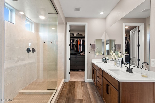 12430 Foxtail Run Ave, Las Vegas, NV 89138 - bathroom with wood finished floors, a walk in shower, double vanity, a walk in closet, and baseboards