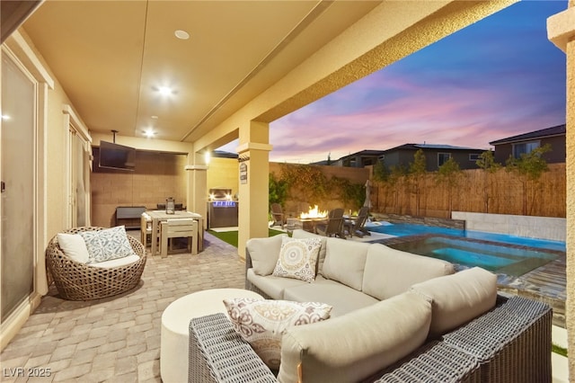 12430 Foxtail Run Ave, Las Vegas, NV 89138 - patio terrace at dusk featuring an outdoor living space with a fire pit, a patio area, outdoor dining area, and a fenced backyard