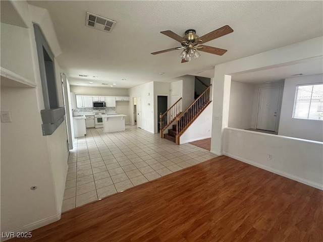 8215 Shell Beach Ct, Las Vegas, NV 89117 - unfurnished living room with light wood-style floors, stairway, baseboards, ceiling fan, and a sink