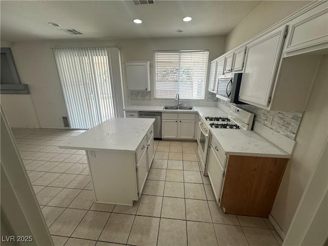 8215 Shell Beach Ct, Las Vegas, NV 89117 - kitchen with a sink, appliances with stainless steel finishes, a kitchen island, light tile patterned floors, and backsplash