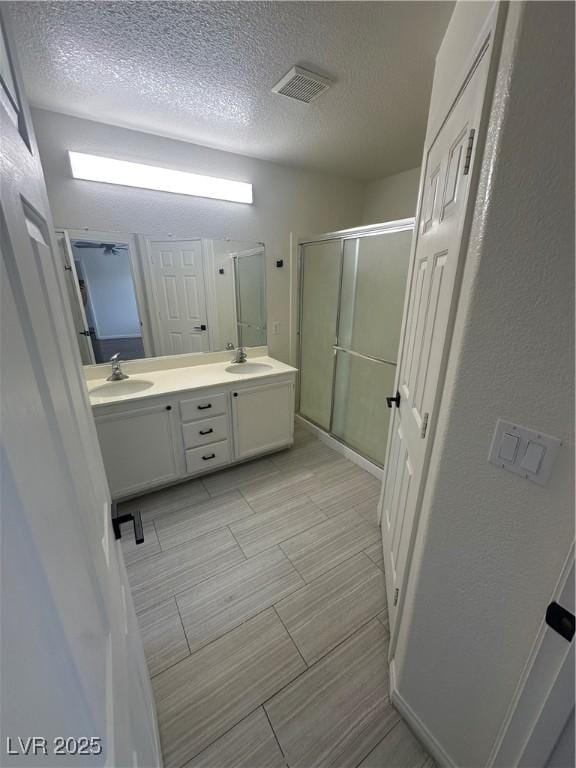 8215 Shell Beach Ct, Las Vegas, NV 89117 - bathroom with a stall shower, a textured ceiling, and double vanity