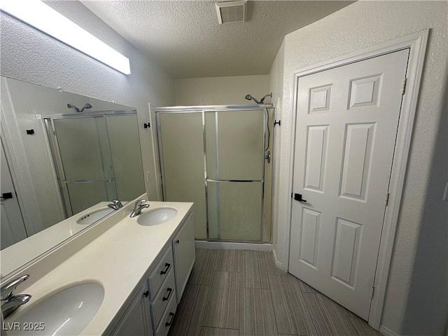 8215 Shell Beach Ct, Las Vegas, NV 89117 - bathroom featuring a stall shower, a textured ceiling, and double vanity