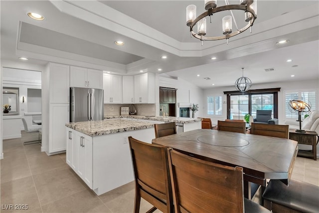 4196 Balmoral Castle Ct, Las Vegas, NV 89141 - kitchen featuring freestanding refrigerator, a chandelier, a kitchen island, a raised ceiling, and recessed lighting