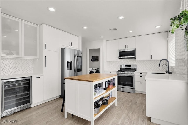 10554 Lilac Tree Ave, Las Vegas, NV 89135 - kitchen featuring wine cooler, appliances with stainless steel finishes, a sink, open shelves, and backsplash