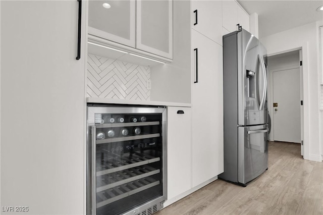 10554 Lilac Tree Ave, Las Vegas, NV 89135 - kitchen featuring stainless steel fridge, beverage cooler, white cabinets, decorative backsplash, and light wood finished floors