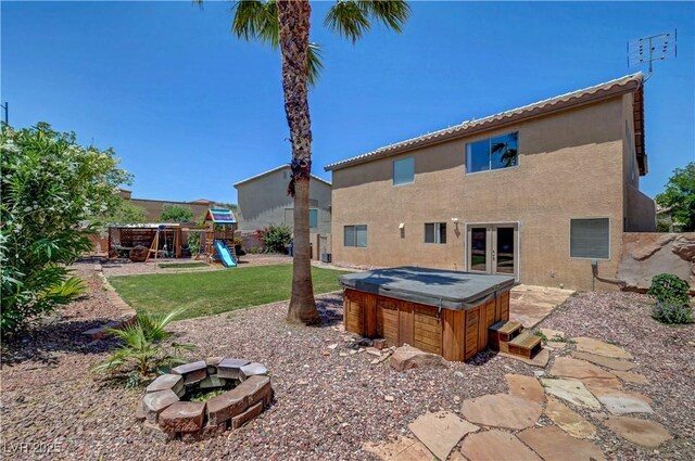 8333 Valley Stream Ave, Las Vegas, NV 89131 - back of property with a hot tub, a playground, a fire pit, and stucco siding
