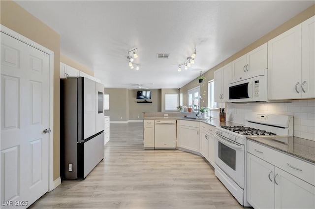 8333 Valley Stream Ave, Las Vegas, NV 89131 - kitchen featuring white appliances, a peninsula, a sink, white cabinets, and baseboards