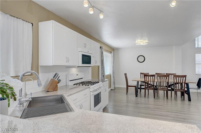 8333 Valley Stream Ave, Las Vegas, NV 89131 - kitchen featuring white appliances, a sink, decorative backsplash, light countertops, and white cabinets