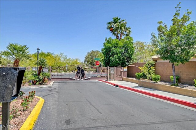 8333 Valley Stream Ave, Las Vegas, NV 89131 - view of asphalt road with a gate, curbs, and a gated entry