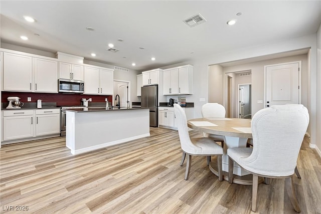 171 Palm Fox Ct, Henderson, NV 89011 - kitchen with stainless steel appliances, dark countertops, light wood finished floors, white cabinets, and recessed lighting