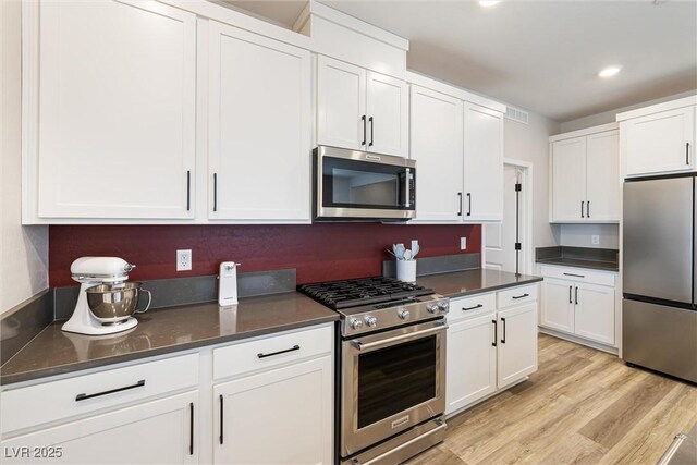 171 Palm Fox Ct, Henderson, NV 89011 - kitchen featuring appliances with stainless steel finishes, dark countertops, white cabinetry, light wood-type flooring, and recessed lighting