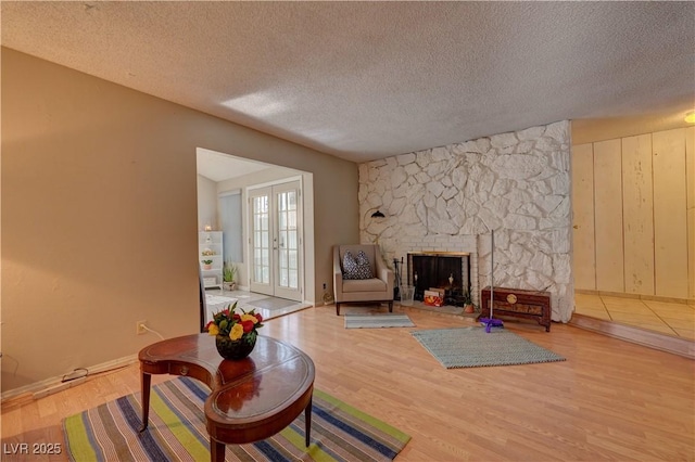 4445 Peterson Dr, Las Vegas, NV 89103 - living room featuring wood finished floors, a textured ceiling, baseboards, and a stone fireplace