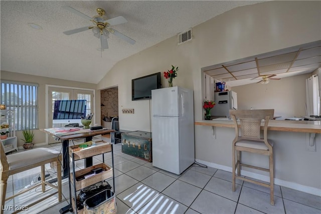 4445 Peterson Dr, Las Vegas, NV 89103 - kitchen with freestanding refrigerator, a ceiling fan, a kitchen breakfast bar, light tile patterned floors, and lofted ceiling