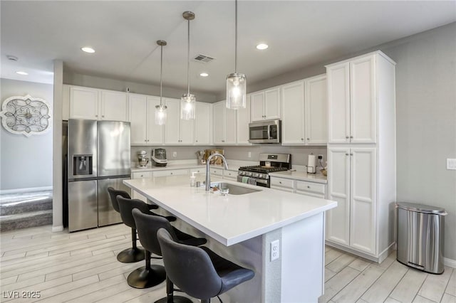 7061 Tilligerry St, North Las Vegas, NV 89084 - kitchen with stainless steel appliances, a sink, wood finish floors, white cabinets, and baseboards