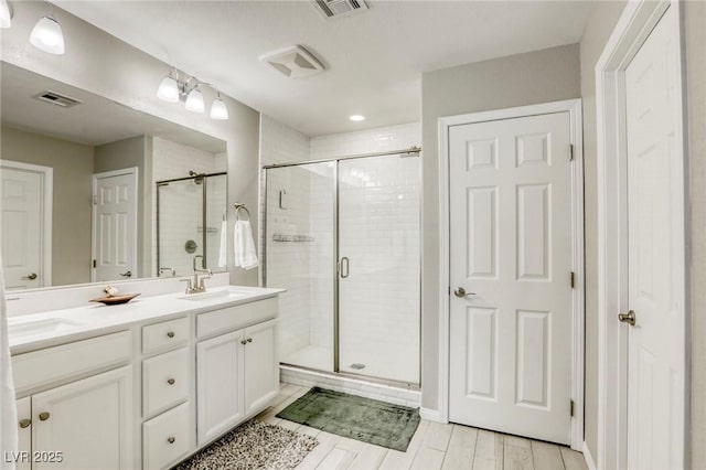 7061 Tilligerry St, North Las Vegas, NV 89084 - bathroom featuring a shower stall, double vanity, and wood finished floors