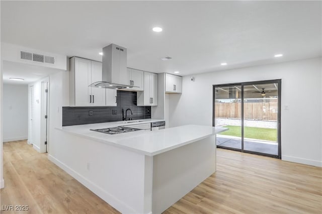 333 Rossmoyne Ave, North Las Vegas, NV 89030 - kitchen featuring island range hood, a sink, light countertops, tasteful backsplash, and light wood-style floors