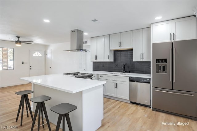 333 Rossmoyne Ave, North Las Vegas, NV 89030 - kitchen with appliances with stainless steel finishes, island exhaust hood, a breakfast bar area, a sink, and backsplash