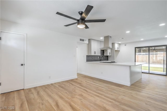 333 Rossmoyne Ave, North Las Vegas, NV 89030 - kitchen featuring wall chimney exhaust hood, light countertops, light wood-type flooring, white cabinets, and baseboards