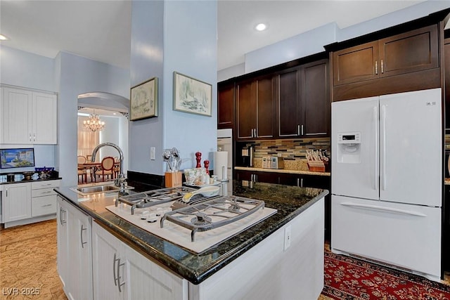 6230 Calm Brook Ct, Las Vegas, NV 89149 - kitchen with white appliances, a sink, a chandelier, dark brown cabinetry, and dark stone counters