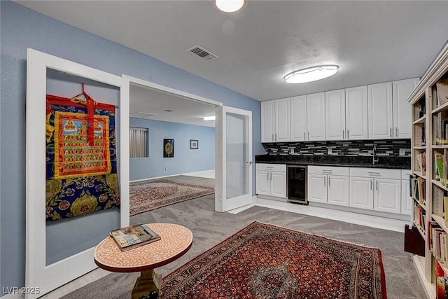 6230 Calm Brook Ct, Las Vegas, NV 89149 - kitchen featuring wine cooler, light colored carpet, white cabinets, a sink, and dark countertops