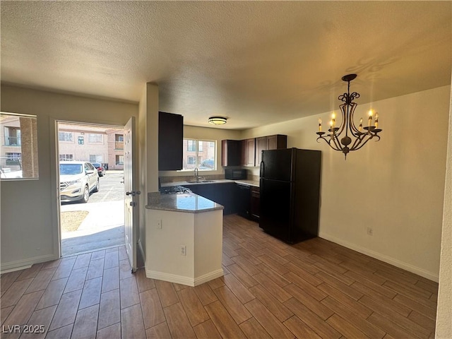 1505 Frank Aved St Unit 101, Las Vegas, NV 89110 - kitchen with black appliances, wood finished floors, a chandelier, hanging light fixtures, and a textured ceiling
