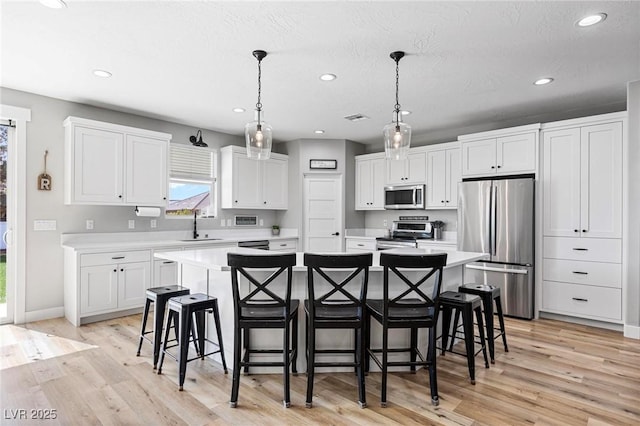 1395 Logandale Dr, Logandale, NV 89021 - kitchen with stainless steel appliances, a spacious island, light countertops, recessed lighting, and white cabinets