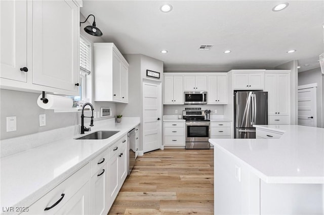 1395 Logandale Dr, Logandale, NV 89021 - kitchen with appliances with stainless steel finishes, a sink, recessed lighting, light wood-style floors, and white cabinets