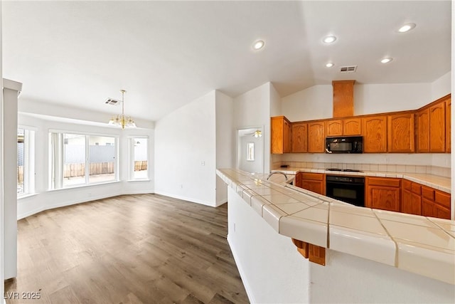 654 Mazelle Ln, Pahrump, NV 89060 - kitchen with black appliances, tile counters, vaulted ceiling, a chandelier, and brown cabinets