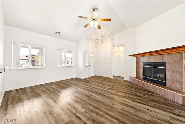 654 Mazelle Ln, Pahrump, NV 89060 - unfurnished living room featuring a ceiling fan, wood finished floors, a tiled fireplace, baseboards, and high vaulted ceiling